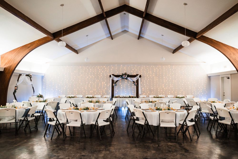 Wedding reception venue with exposed beams, white walls and tables set up for celebration.