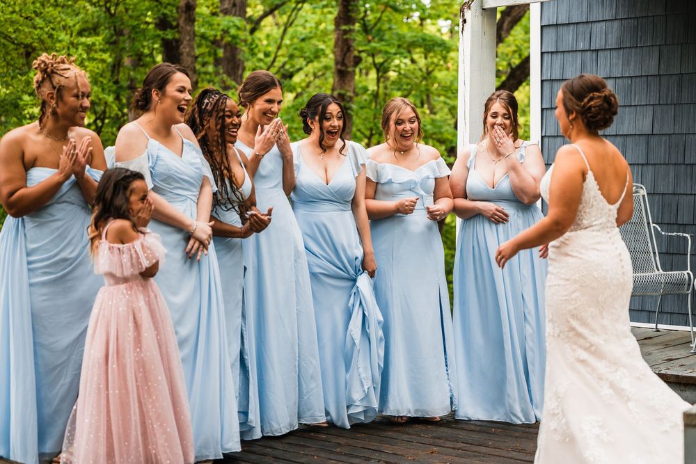 Bridesmaids in matching light blue dresses share a candid moment outdoors.