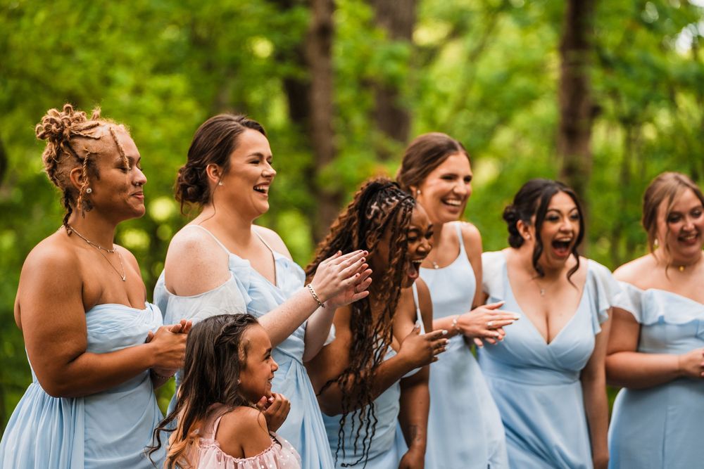 A group wearing light blue dresses shares a joyful moment outdoors during a wedding celebration.