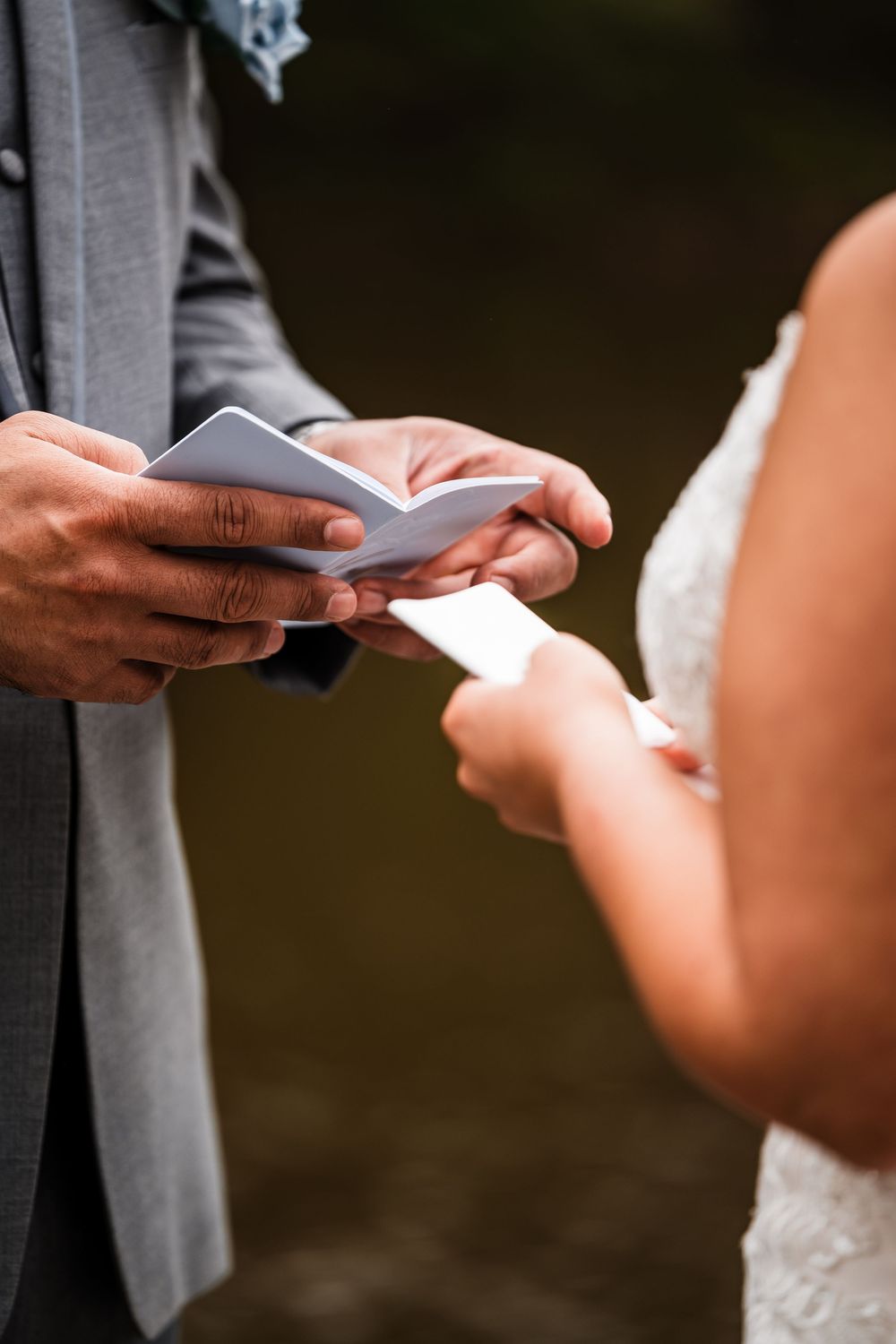 Hands exchanging vows or rings during an outdoor wedding ceremony.