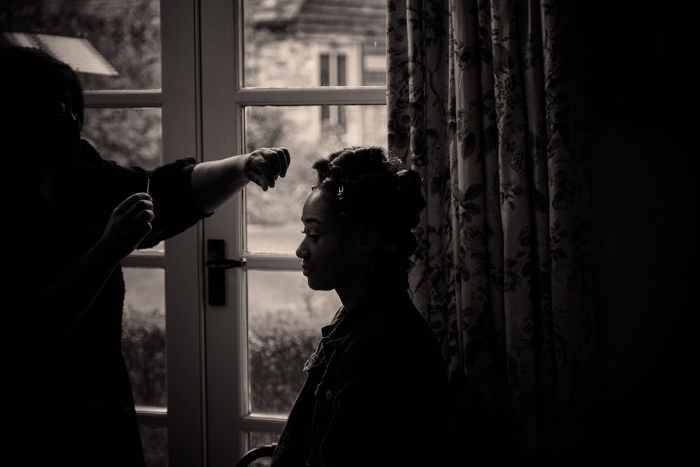 A silhouetted figure in profile by a window as a beam of light illuminates their face in dramatic black and white.