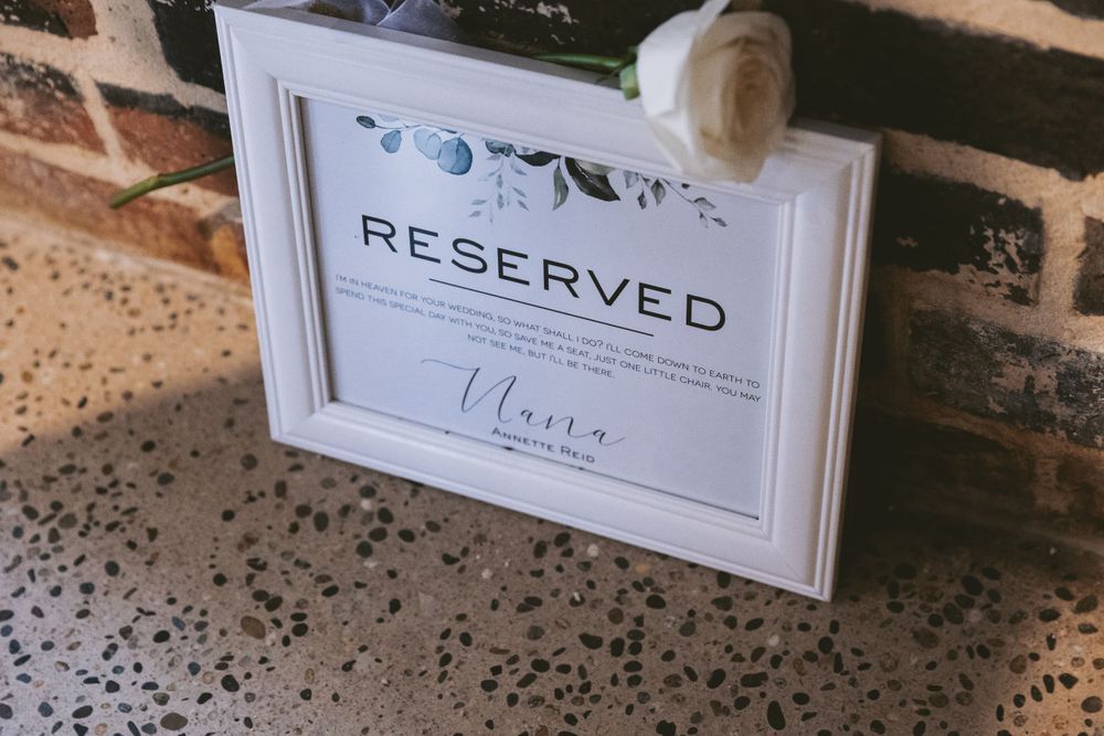 White framed 'Reserved' sign with decorative flourishes displayed at a wedding venue.