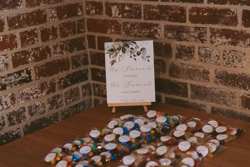 Wedding favor display with small jars arranged neatly against exposed brick wall.