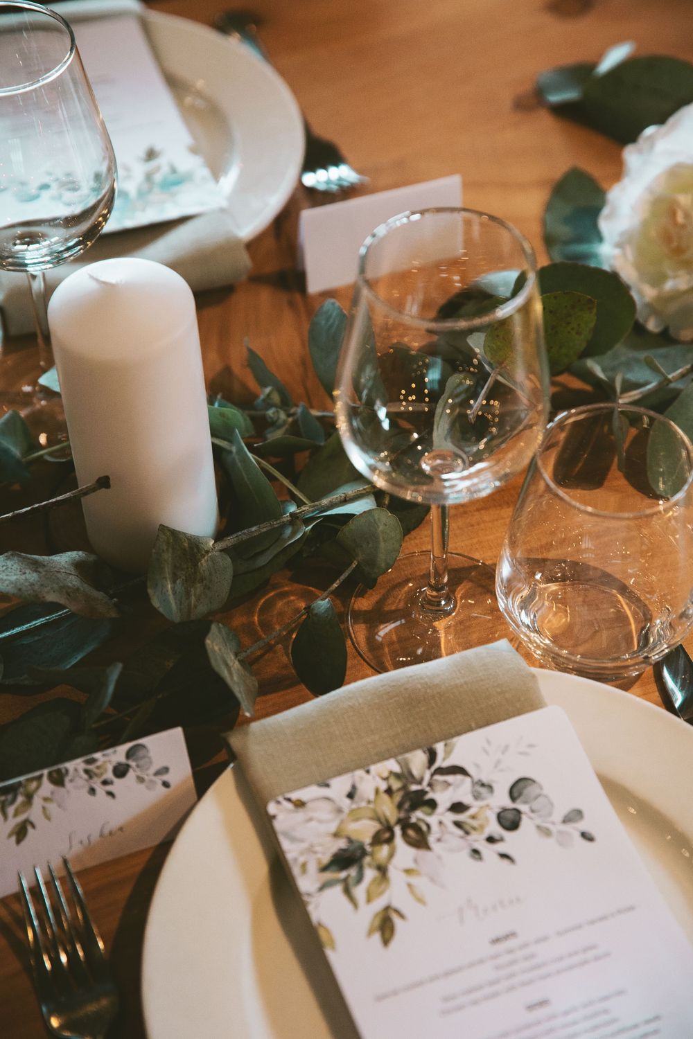 Elegant table setting with wine glasses, menu cards, and floral decorations.