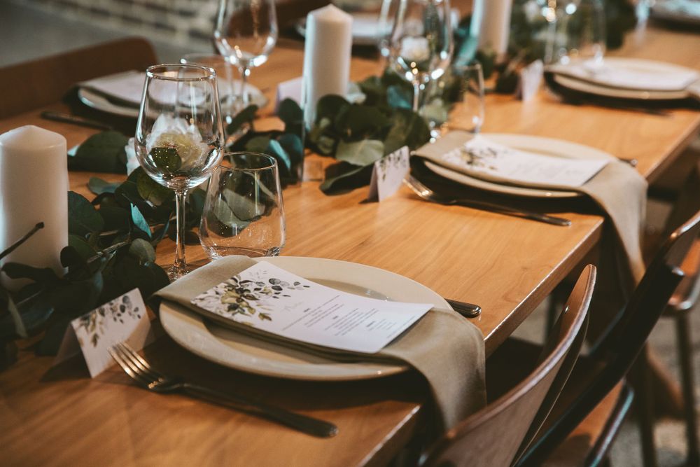 Wedding table setting with white napkins, greenery, and floral menu cards.