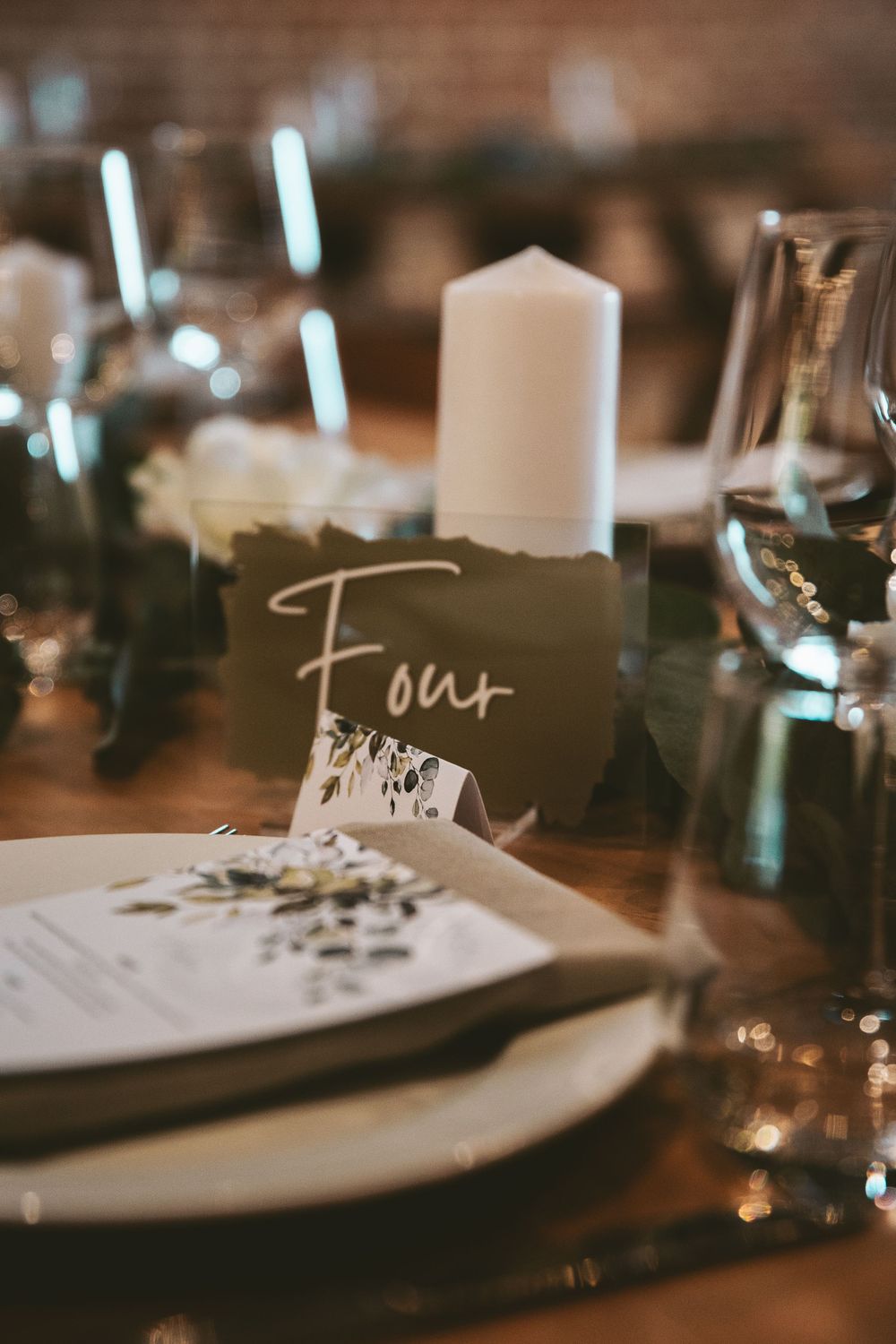 Table number four card with candlelight and place settings at wedding reception.