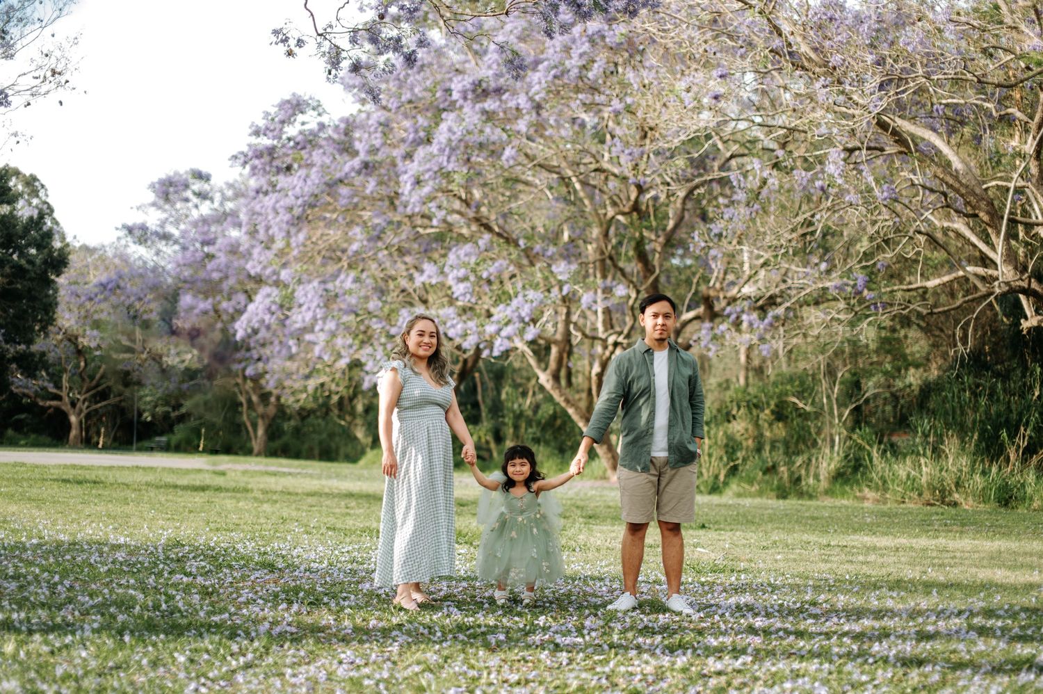 A sunny outdoor photo in a park with blooming cherry trees and figures standing together in spring casual attire.
