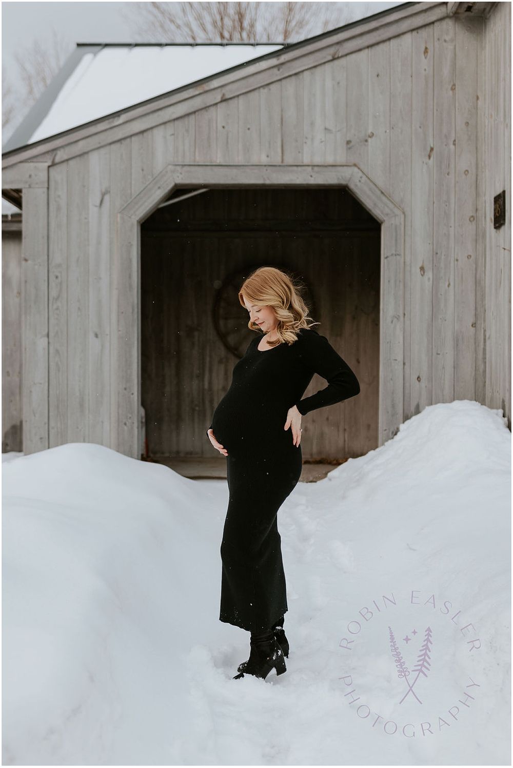 Woman in a black dress taking maternity photos in NH