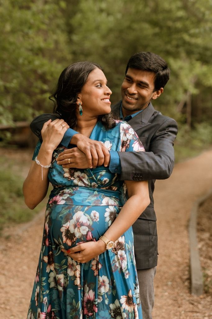 A romantic couple embraces on a woodland path during an outdoor photo session in fall.