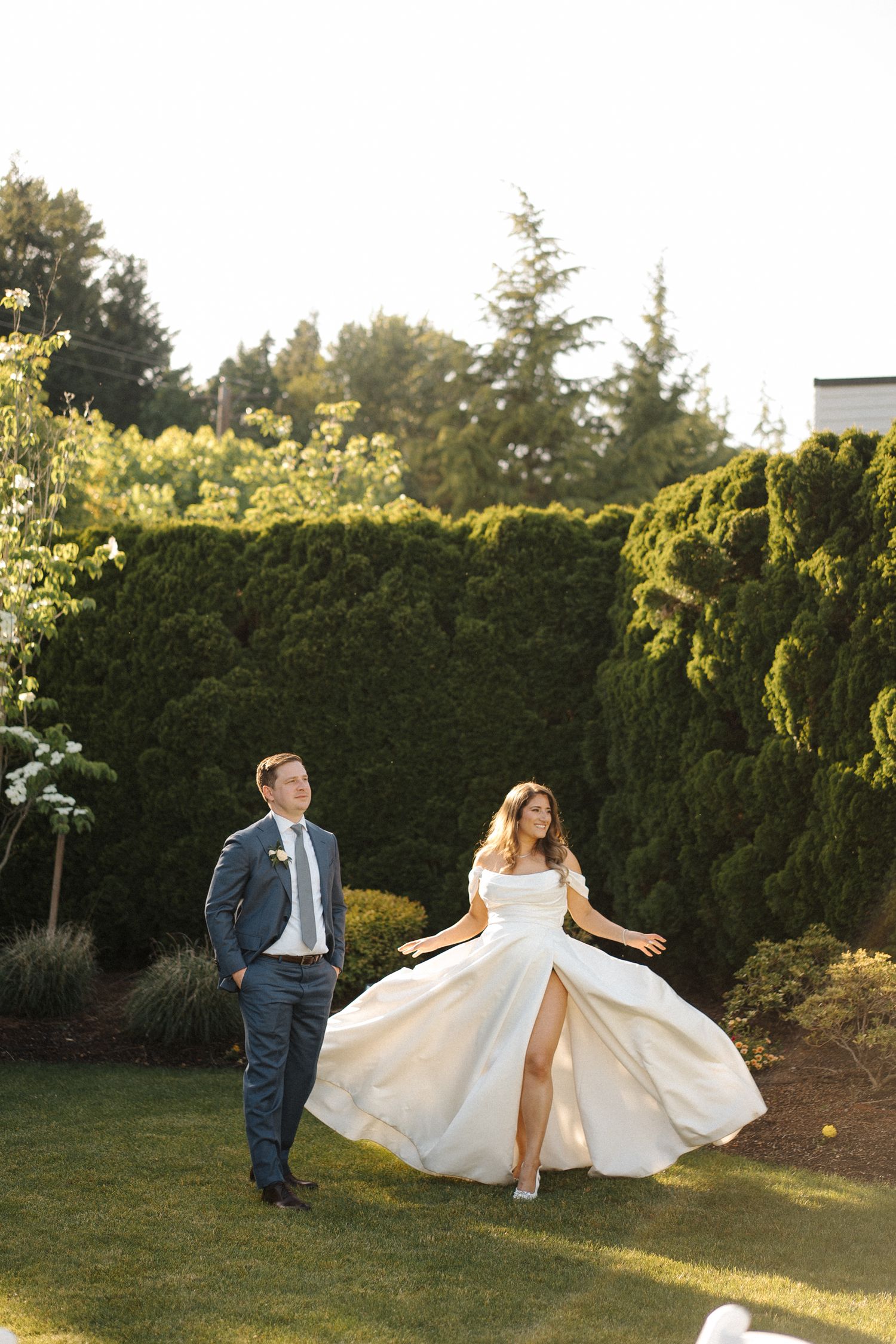 Wedding couple dances and twirls in a garden at sunset with elegant dress movements creating romantic silhouettes.