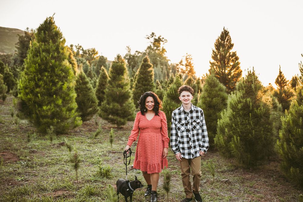 Couple walks together through evergreen trees at sunset during golden hour in winter landscape.