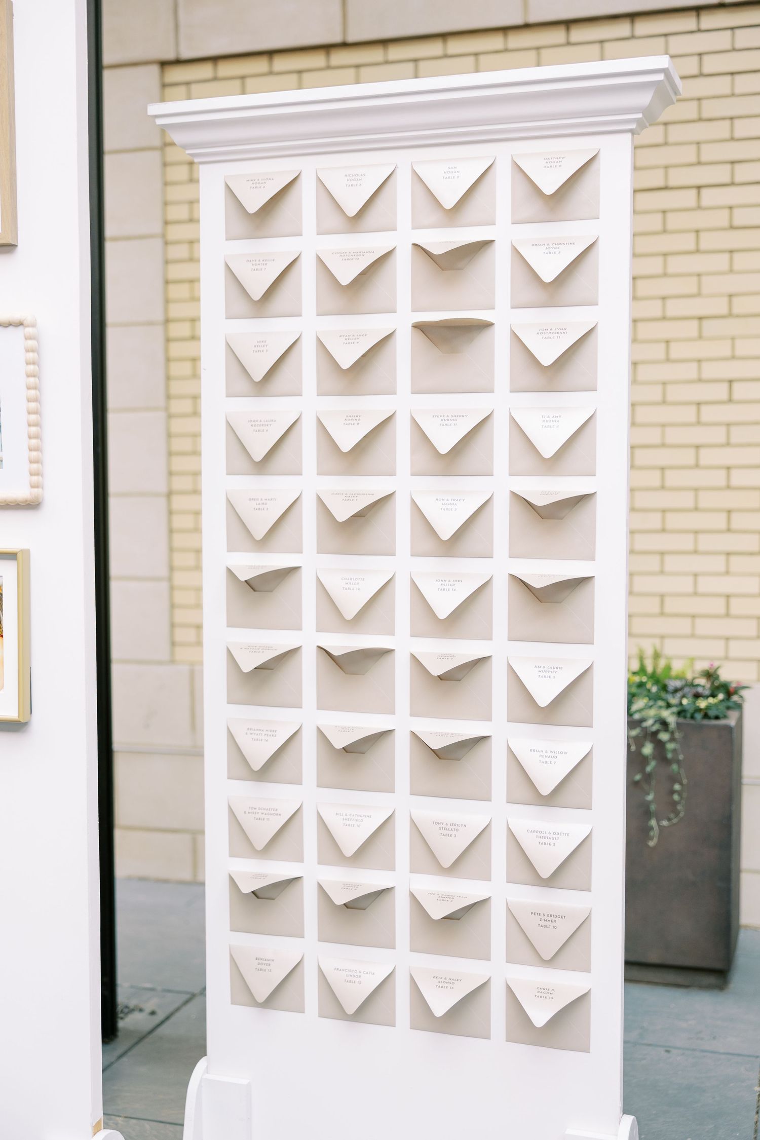 Modern white accent wall with geometric triangular cutouts creating a dimensional pattern against light brick exterior.