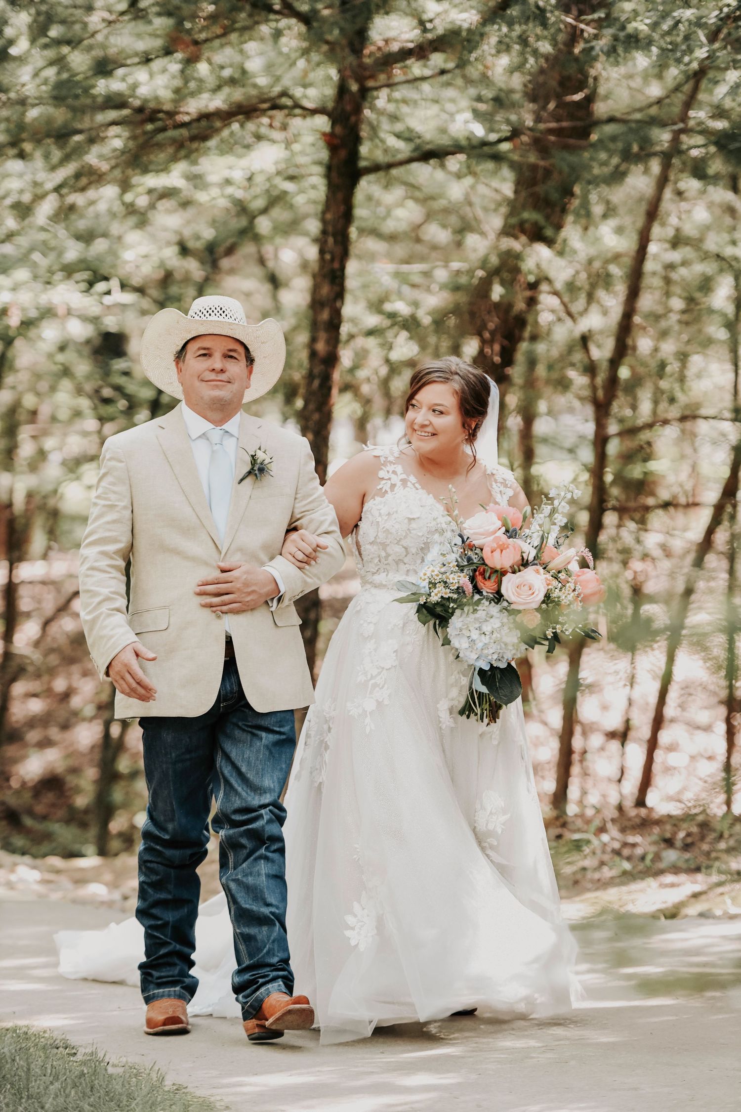 Bride looking at groom as she walks arm-in-arm with her father