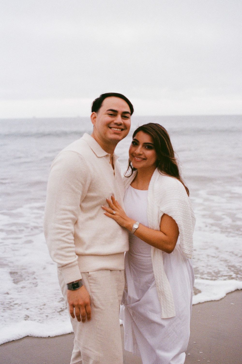 Holding hands and walking through wet sand during engagement session.