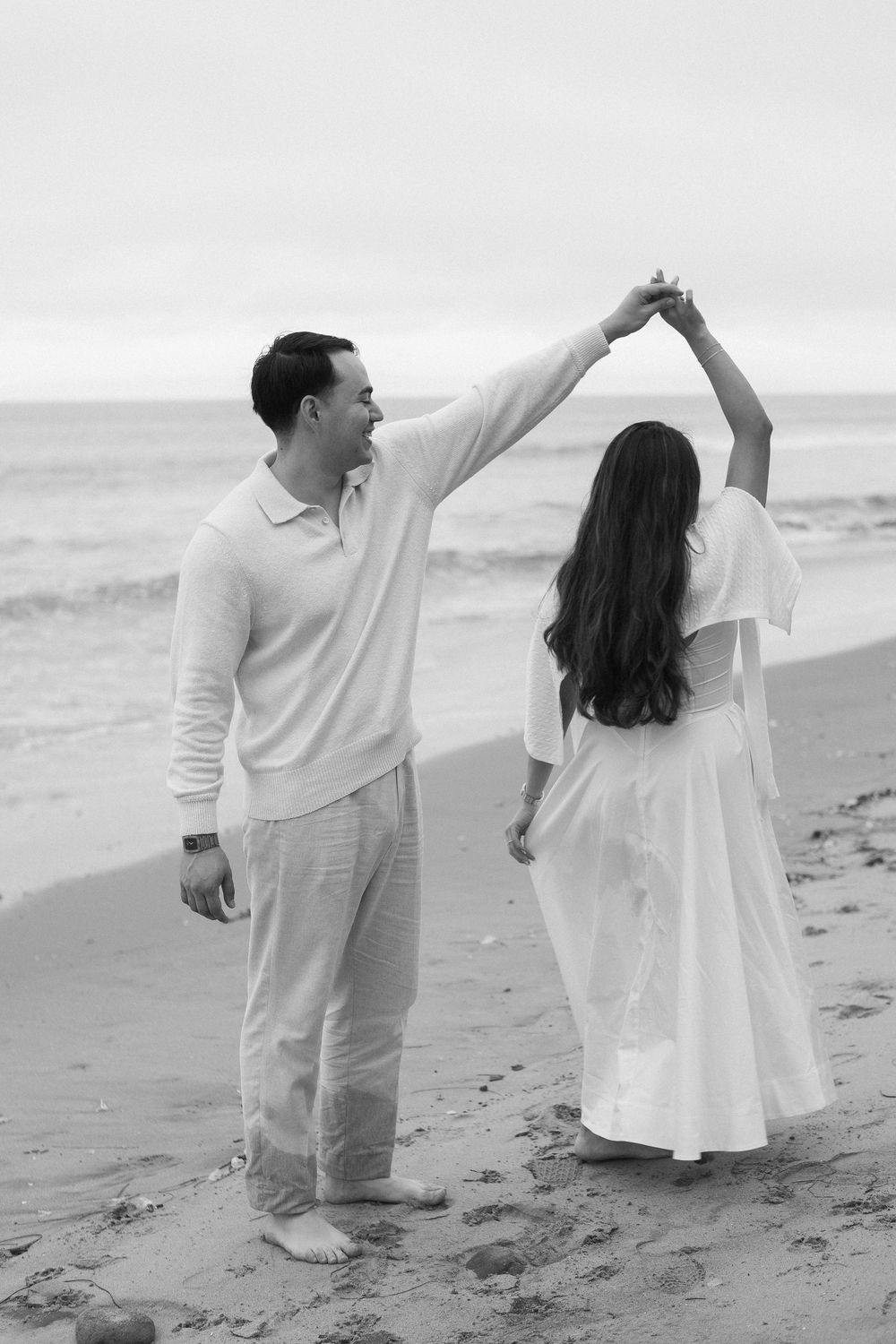 Silhouette of couple standing by waves after proposal.