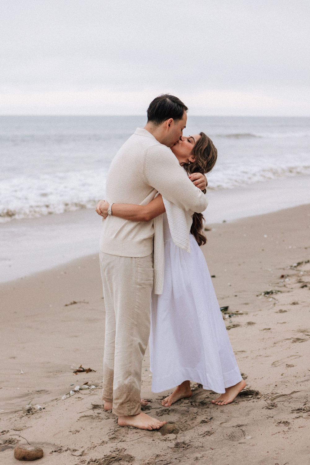 Stephanie smiling as Hector proposes at sunset-colored beach