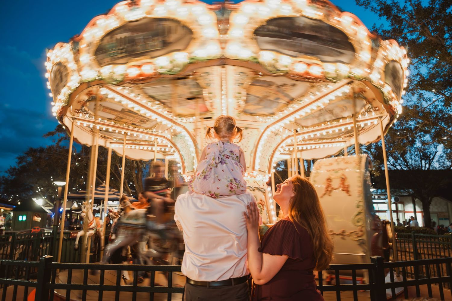 John & Emily anniversary photos at Disney Springs with baby Ripley, in front of the carousel. Cred: LexTakePix
