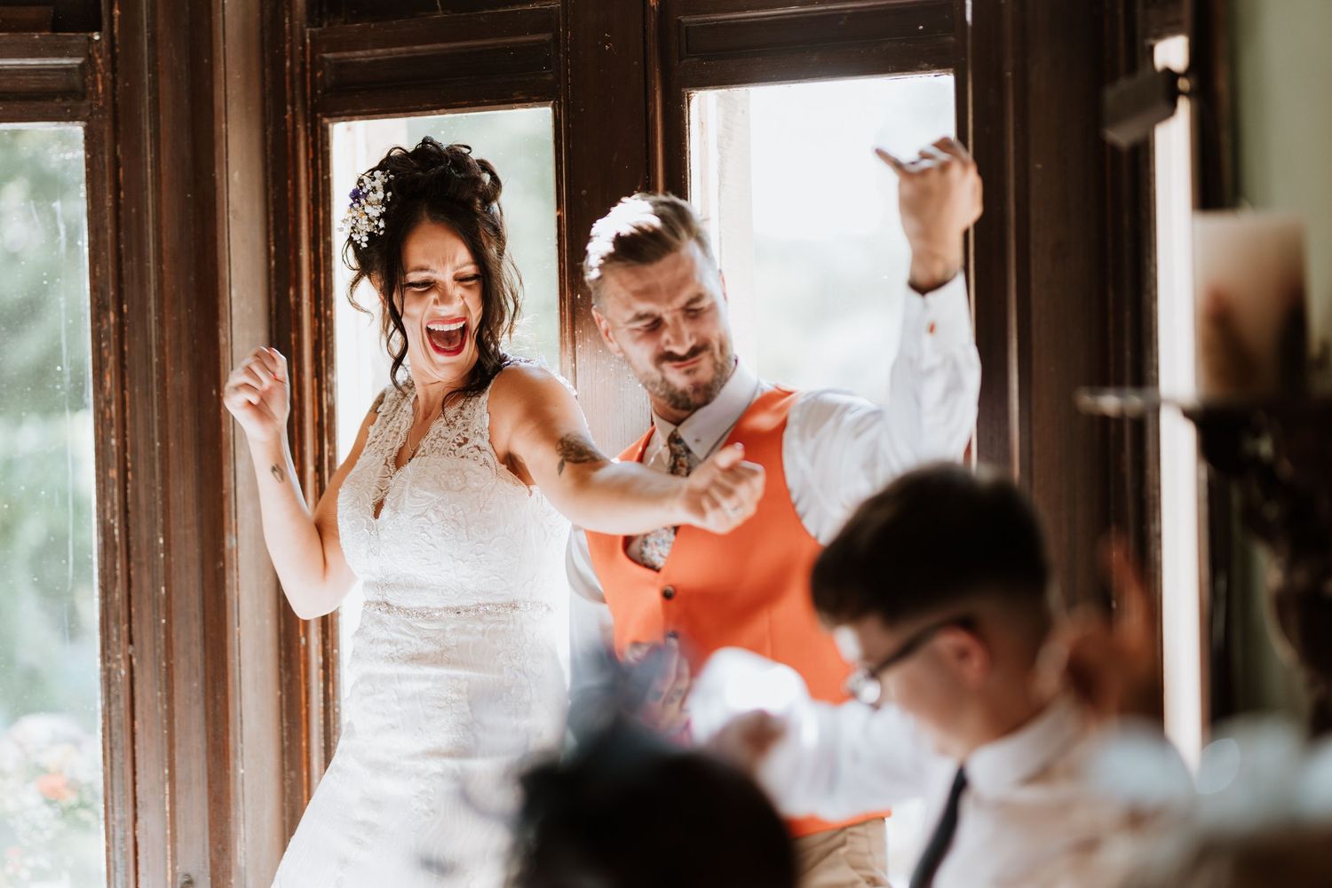Energetic dancing and celebrating at a joyful wedding reception in a warm-lit venue.