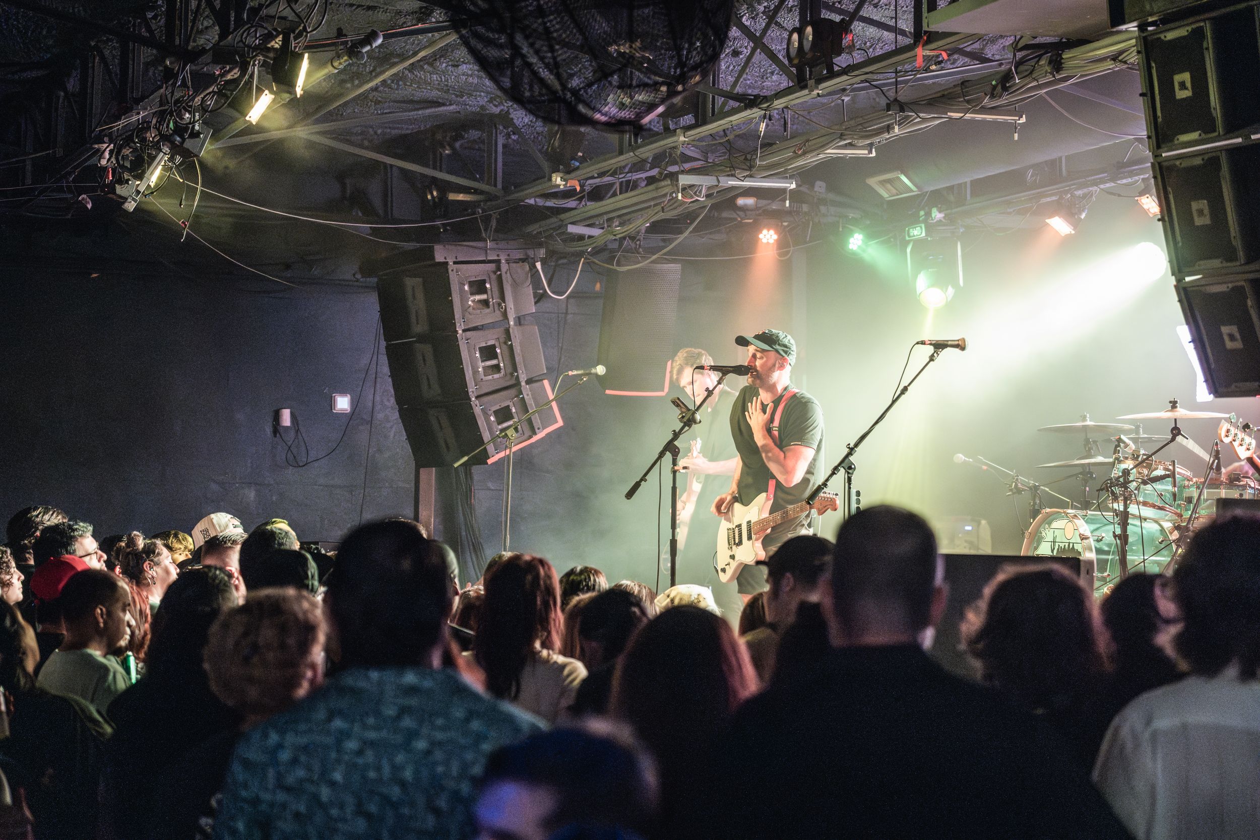 Wide shot of a concert venue with stage lighting and silhouetted audience members.