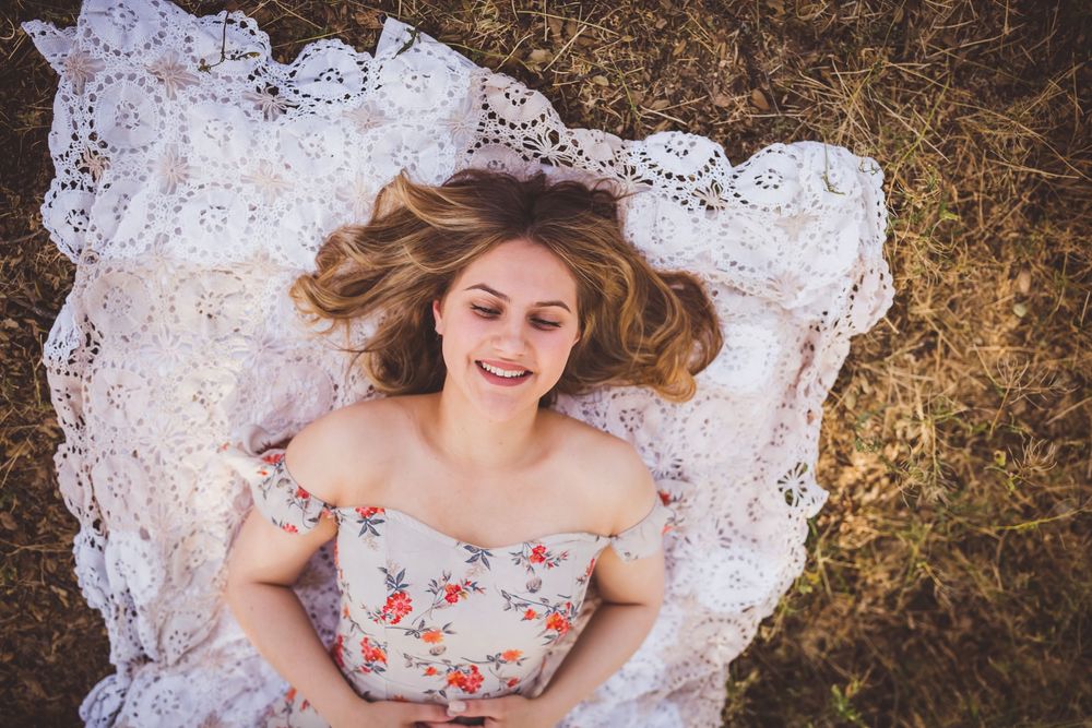Floral dress spreads out in a circle against brown ground, with white lace edges creating a romantic vintage aesthetic.