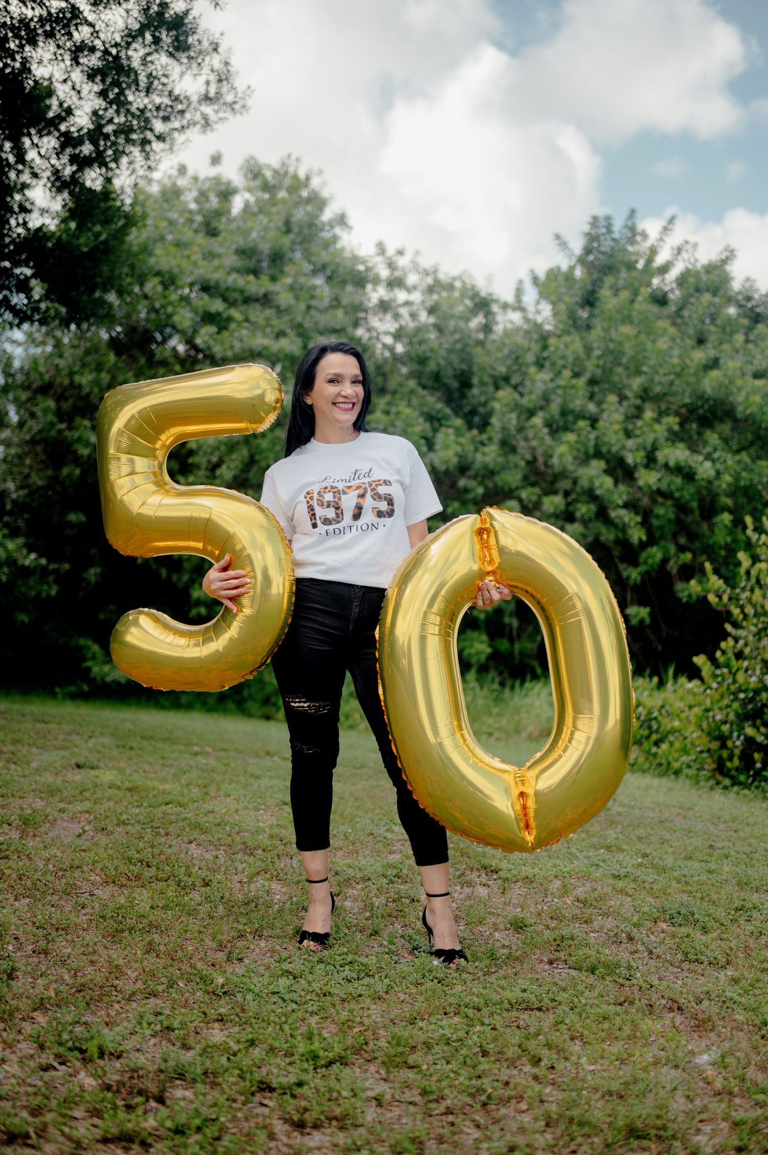 An outdoor photo series showing large gold number balloons spelling out '50' on a grassy lawn.