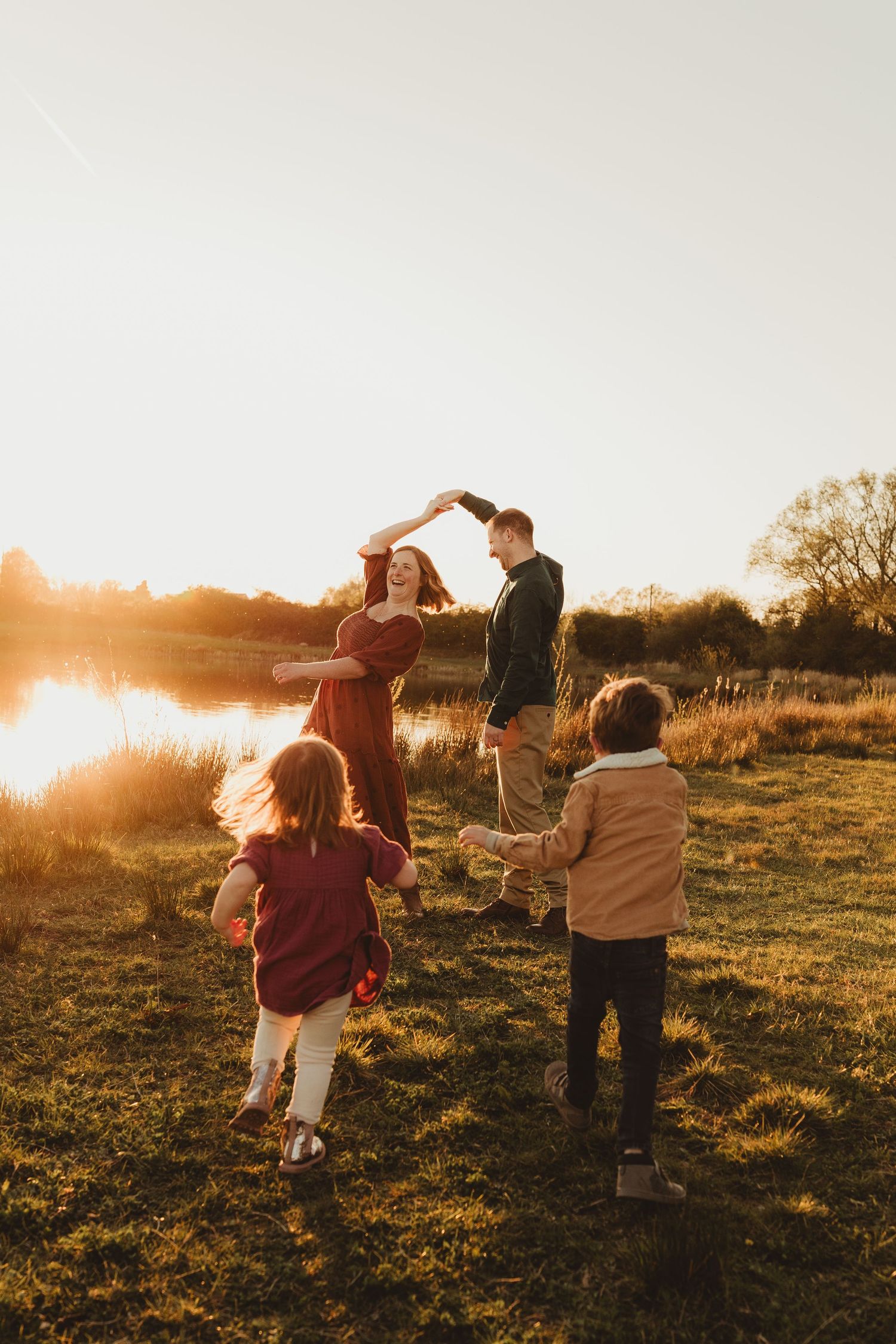 Two children playing and laughing together outdoors in a field at sunset, with one giving a piggyback ride to the other.