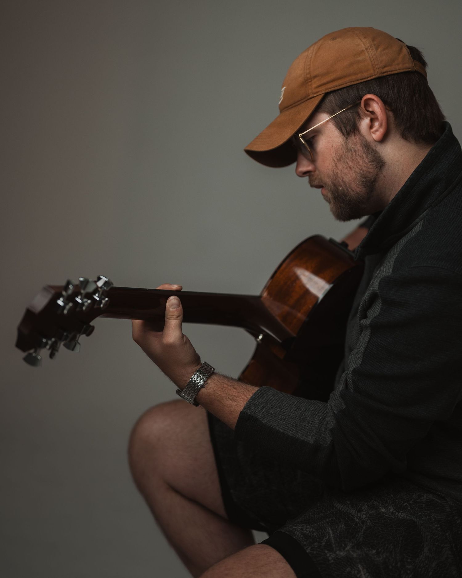 Musicians perform with electric guitars in a studio while being filmed in a multi-panel composition with acoustic guitar details.