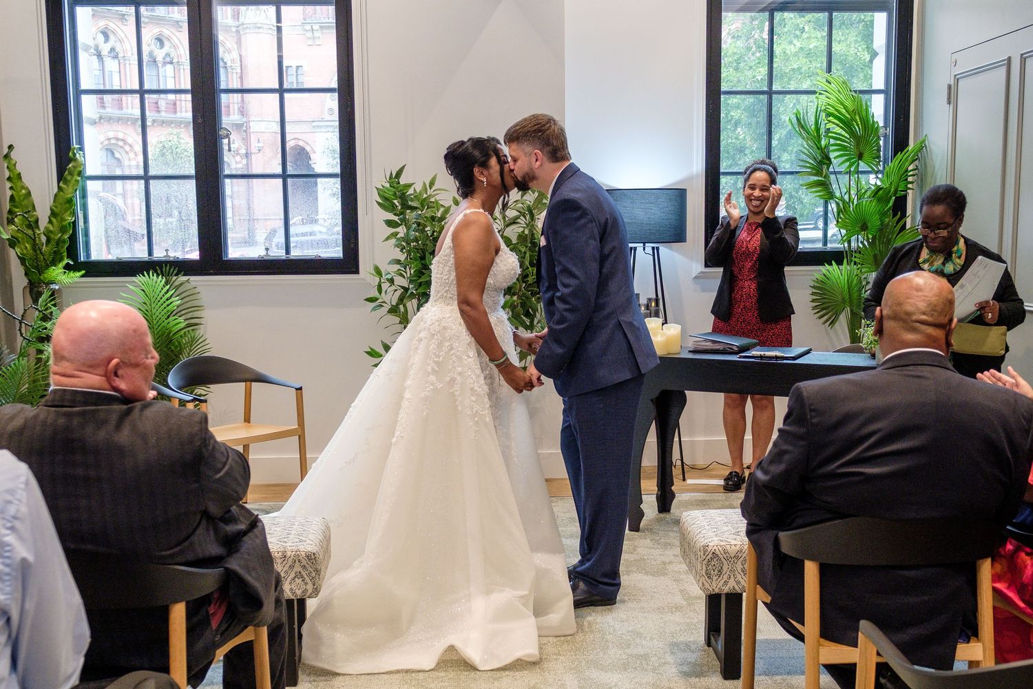 Happy couple sharing intimate moments during their wedding at a bright indoor venue with large windows.