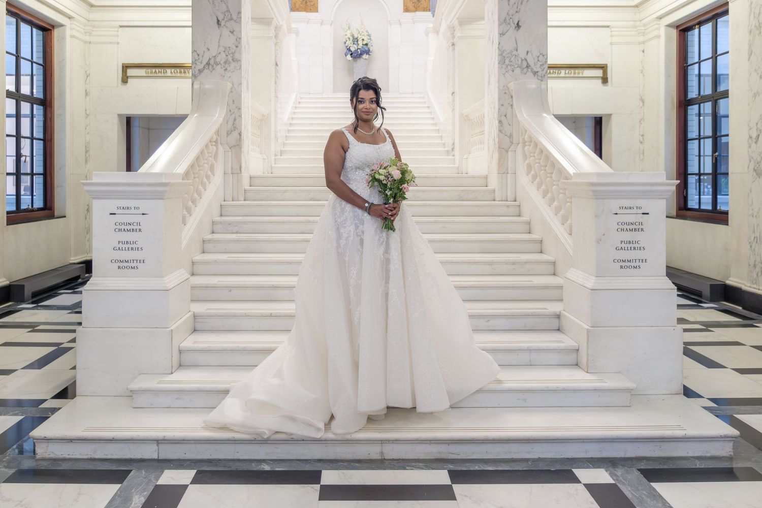 Classic white marble staircase creates stunning architectural backdrop for wedding photos in grand venue.