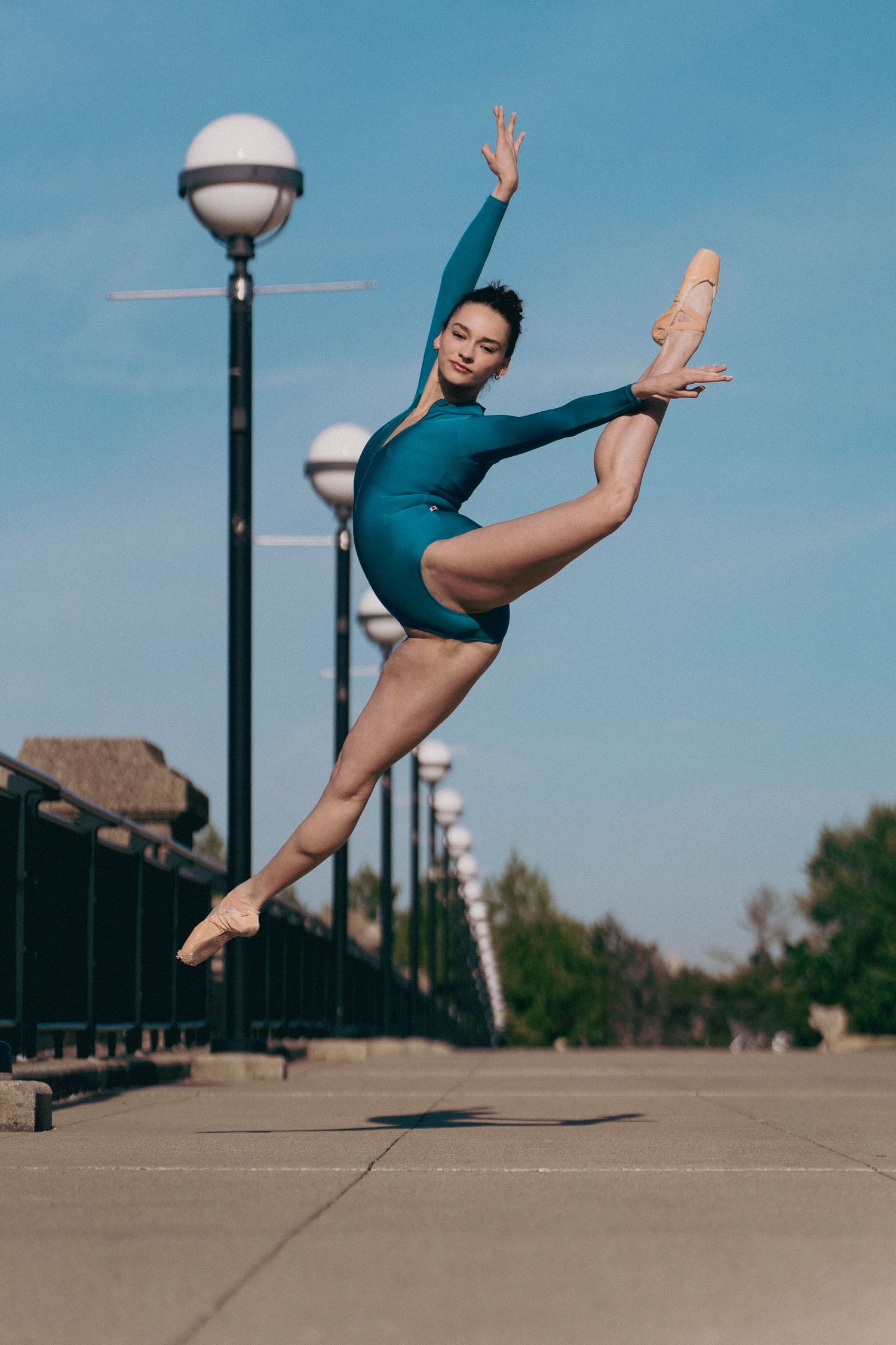Dance portrait of a professional ballerina leaping en pointe near a bridge in Indianapolis park Indy Dance Photographer