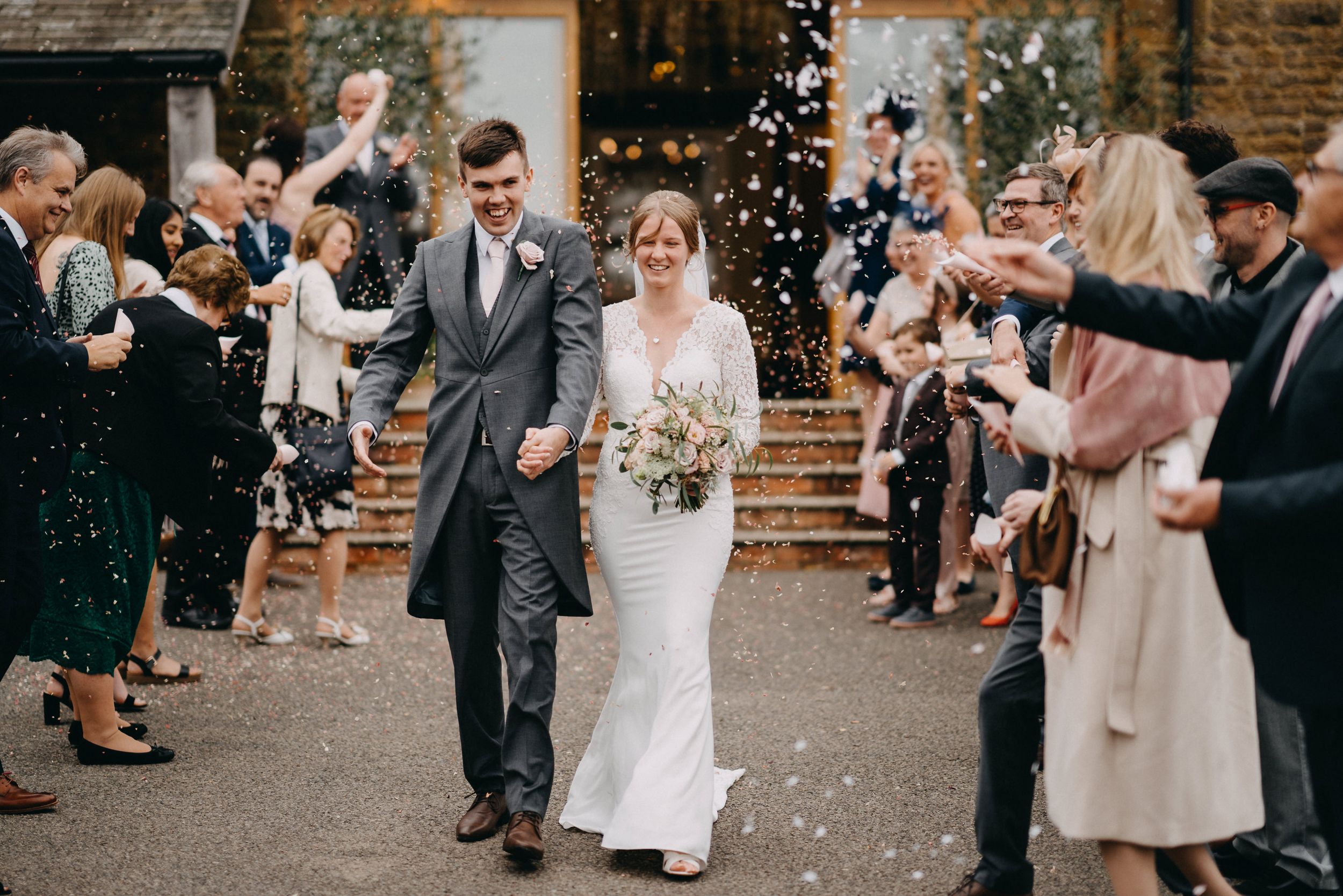 Wedding couple exits venue of Crockwell Farm while guests throw confetti in celebration.