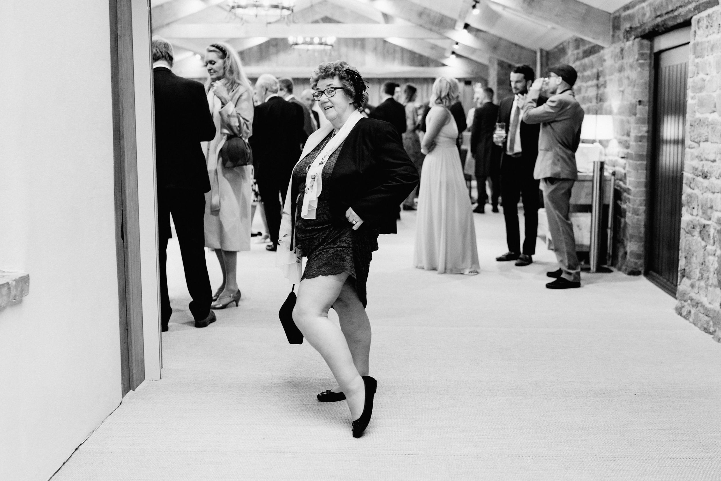 Wedding guest dances energetically in black formalwear at reception venue.