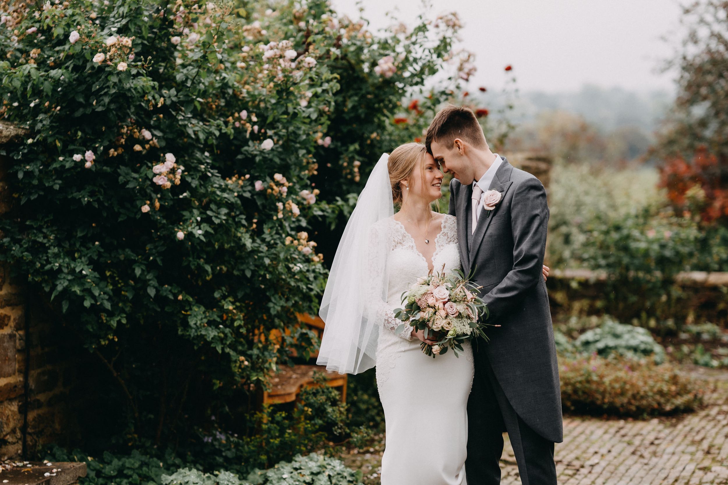 Romantic wedding portrait among blooming garden roses and greenery of Crockwell Farm in Northamptonshire.