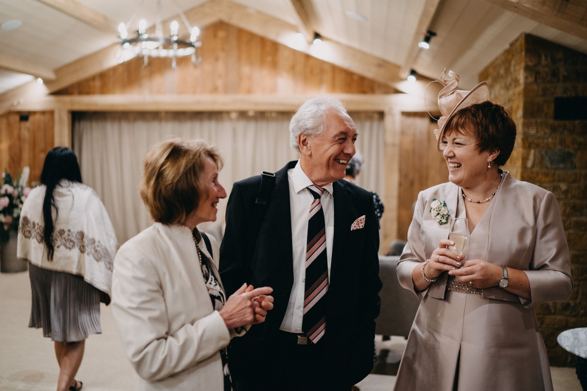 Wedding guests share joyful moment during indoor reception celebration.