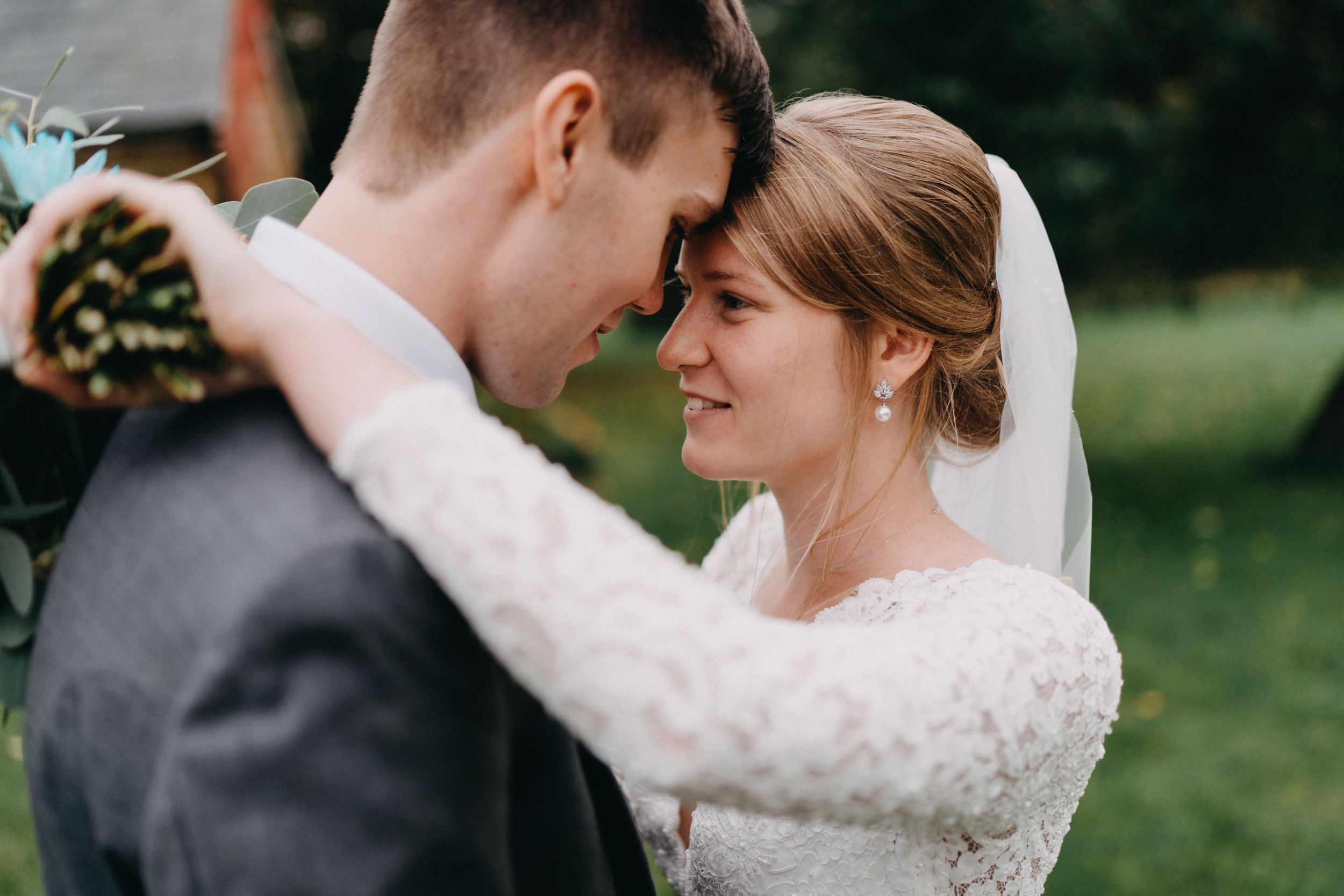 Intimate wedding portrait captures tender moment between newlyweds outdoors.