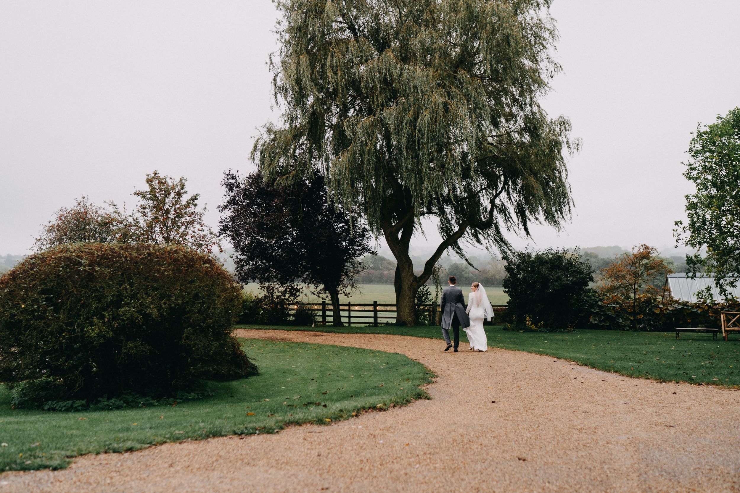 A romantic garden path at Crockwell Farm with willow trees and fencing in the countryside.