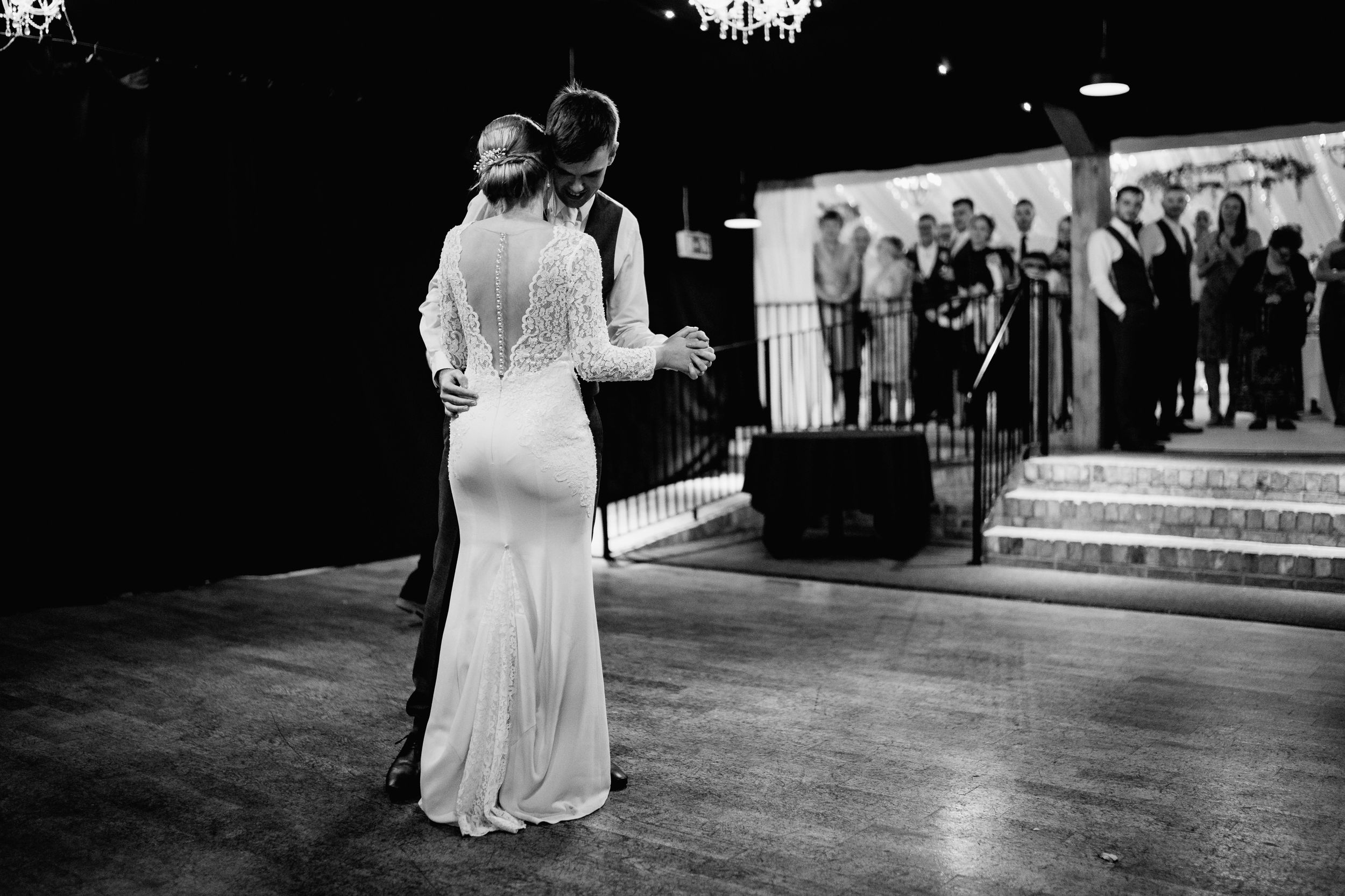 Couple dancing in an elegant white dress and suit during their first dance at a wedding reception.