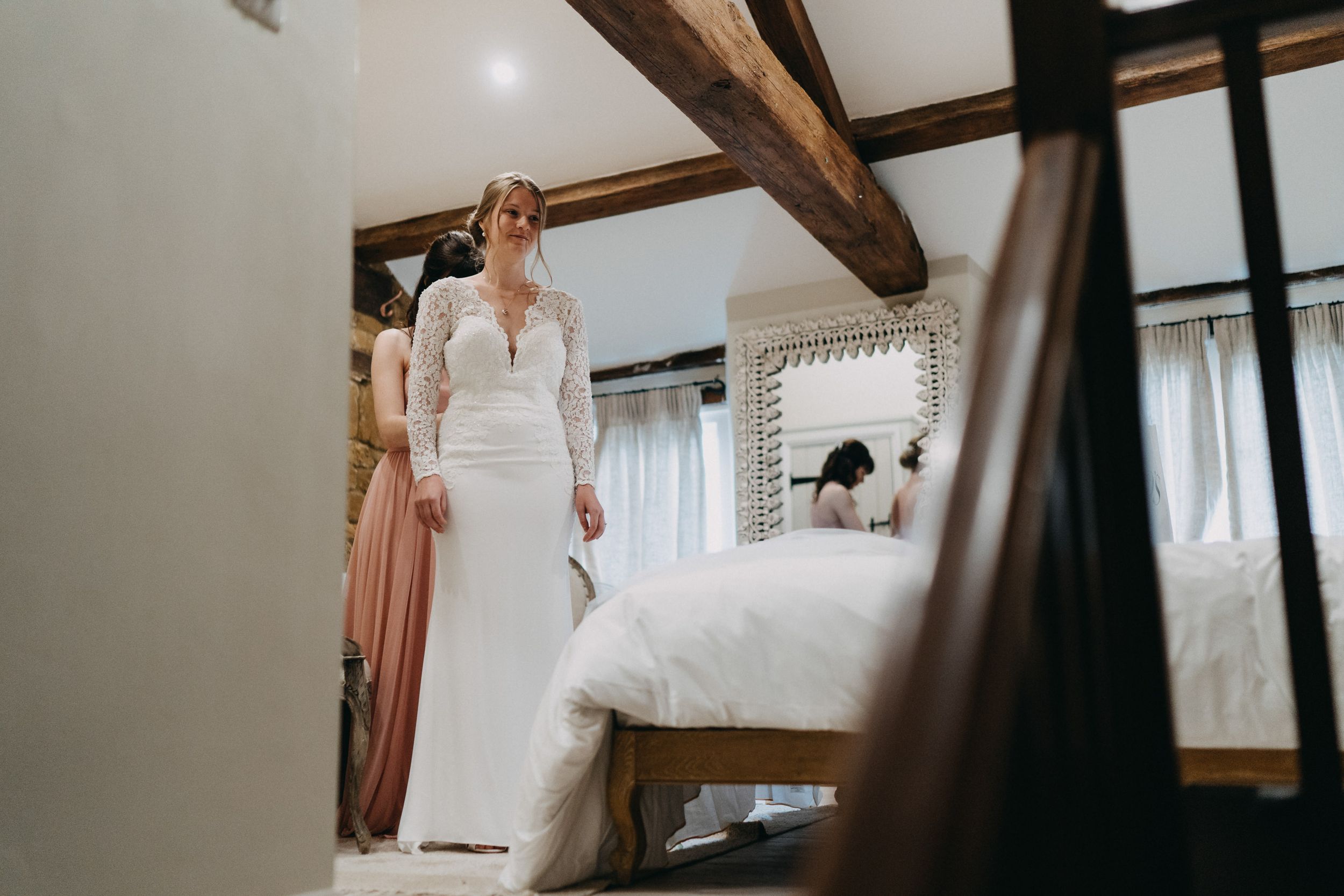 Reflection of wedding dress preparation in a rustic room with wooden beams.