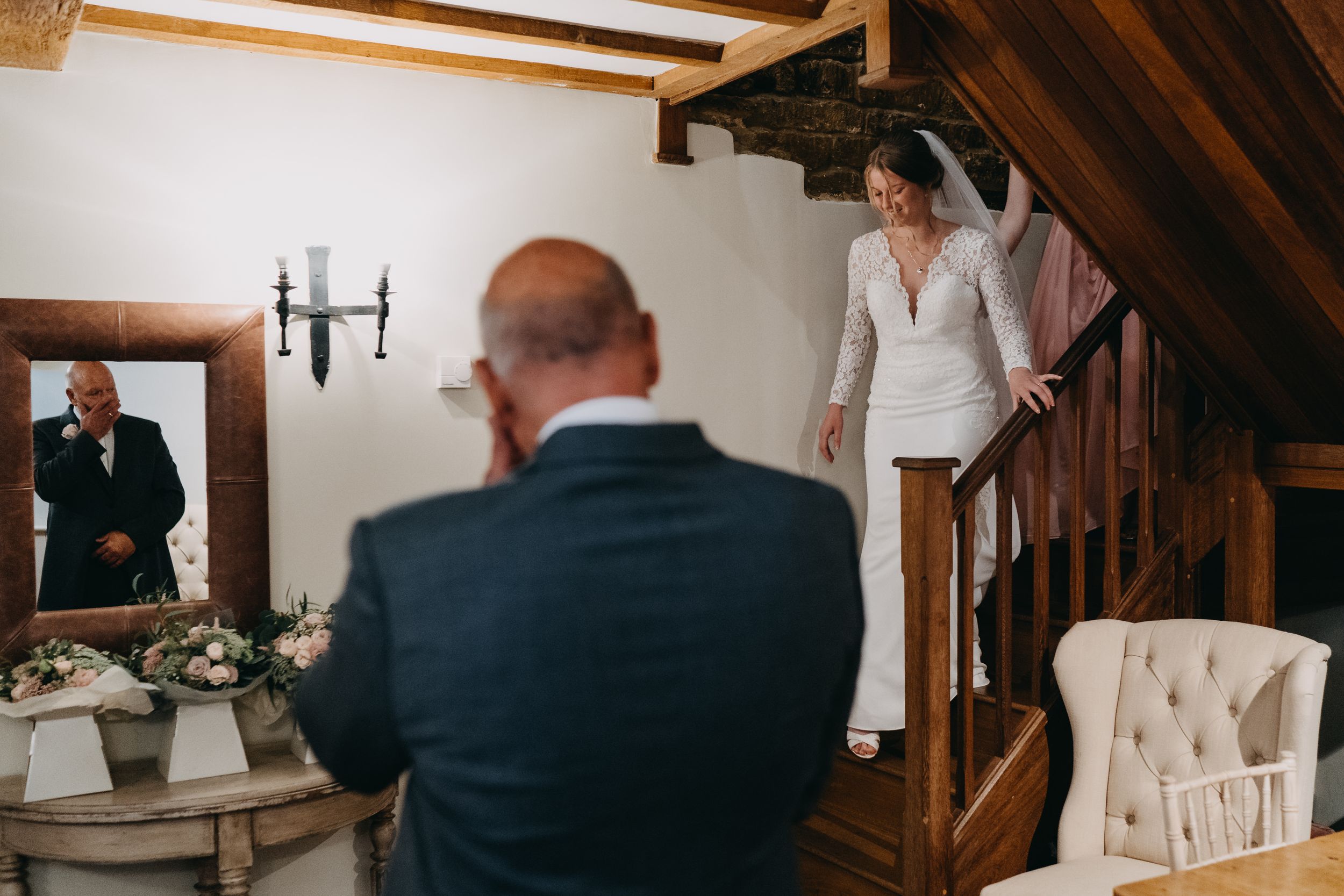 Emotional wedding moment captured on wooden staircase in rustic interior.