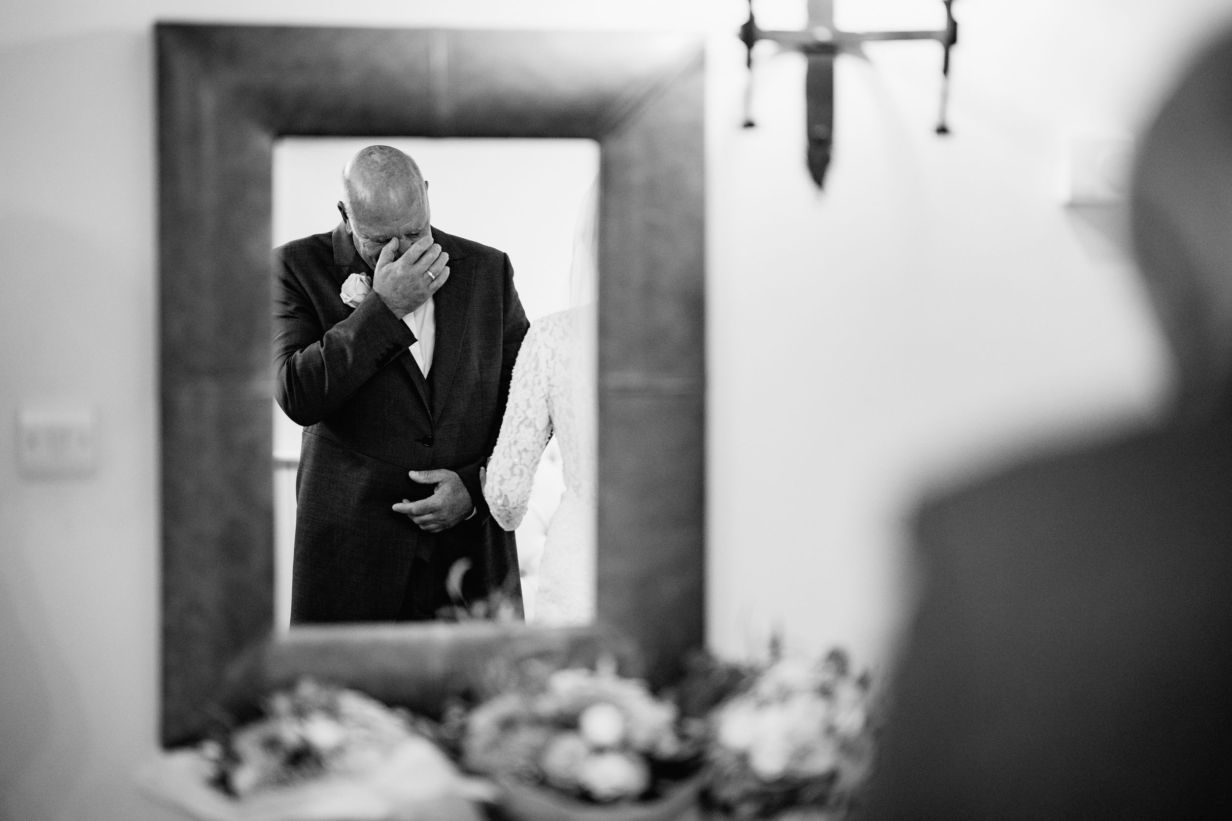 Black and white emotional moment reflected in mirror with flowers in foreground.