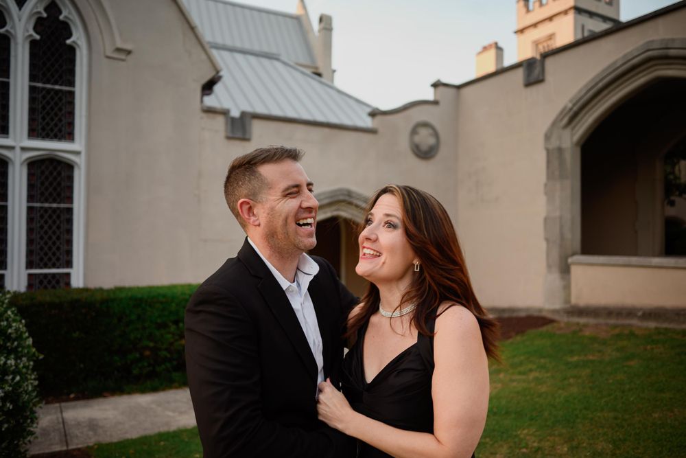 Joyful couple shares a laugh outside historic church building.