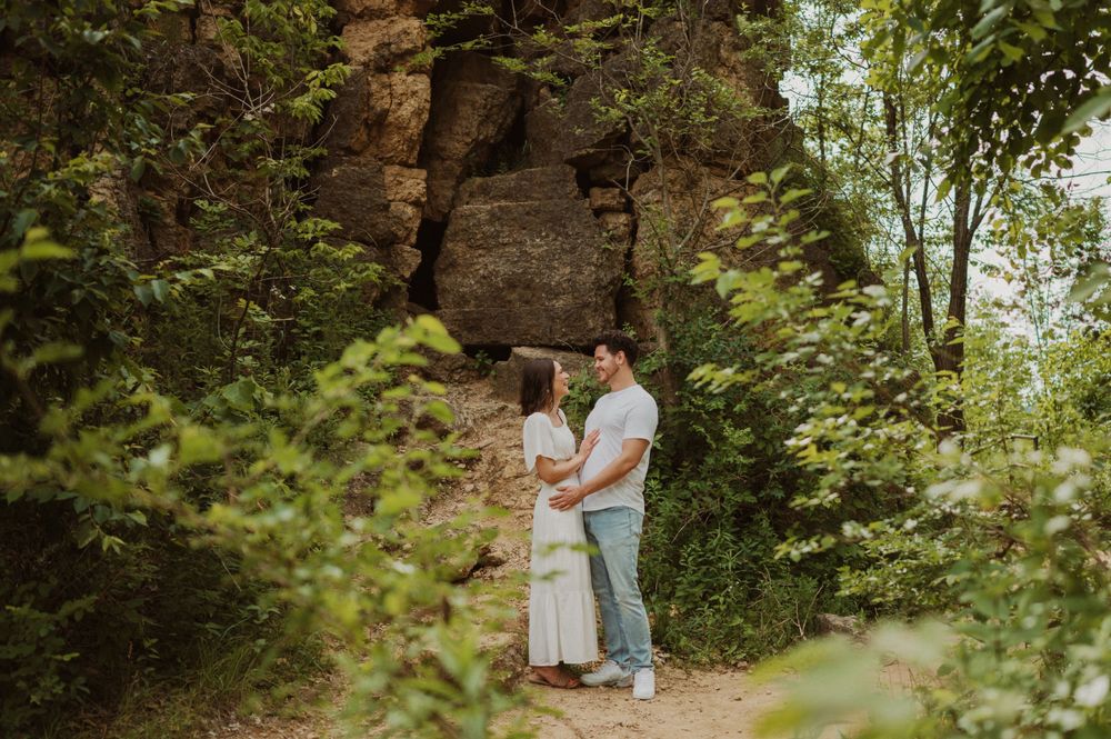 A tender moment between a couple standing against a rocky cliff backdrop in nature.