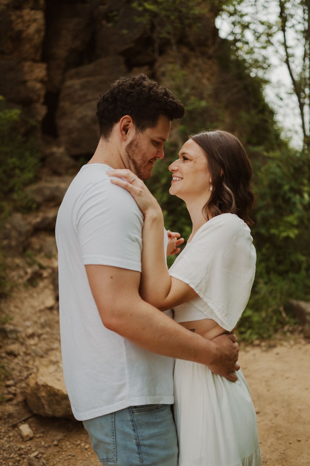 An intimate moment shared between two people in white tops against a natural outdoor setting.