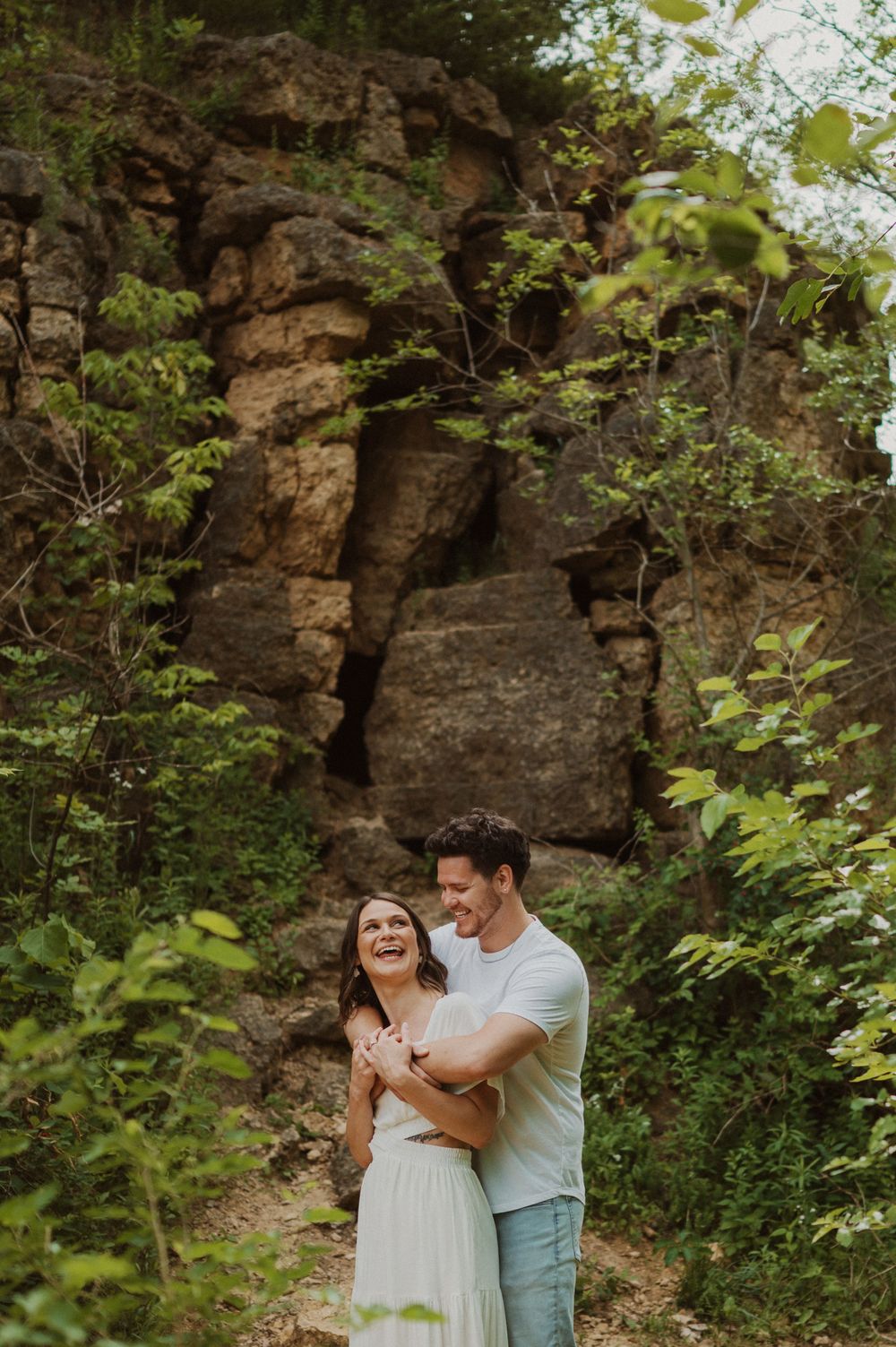 A joyful moment shared between two people on a scenic trail surrounded by rocky cliffs.