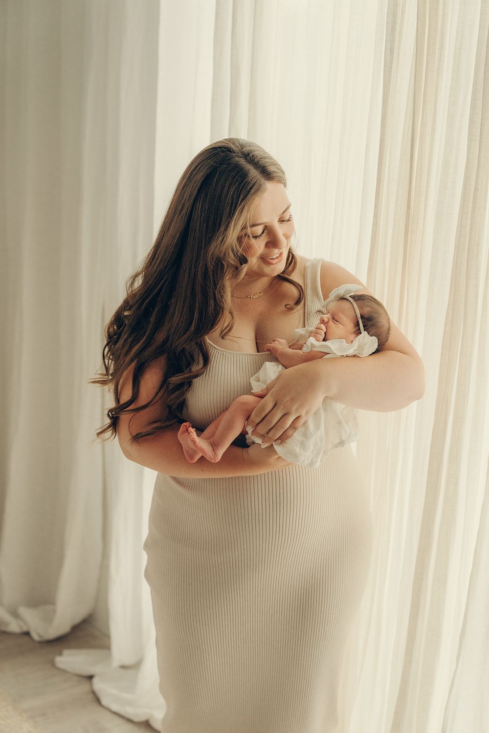 Mom holding a newborn baby during the lifestyle newborn photo session in the Nest studio at Mint Room studio in Toronto