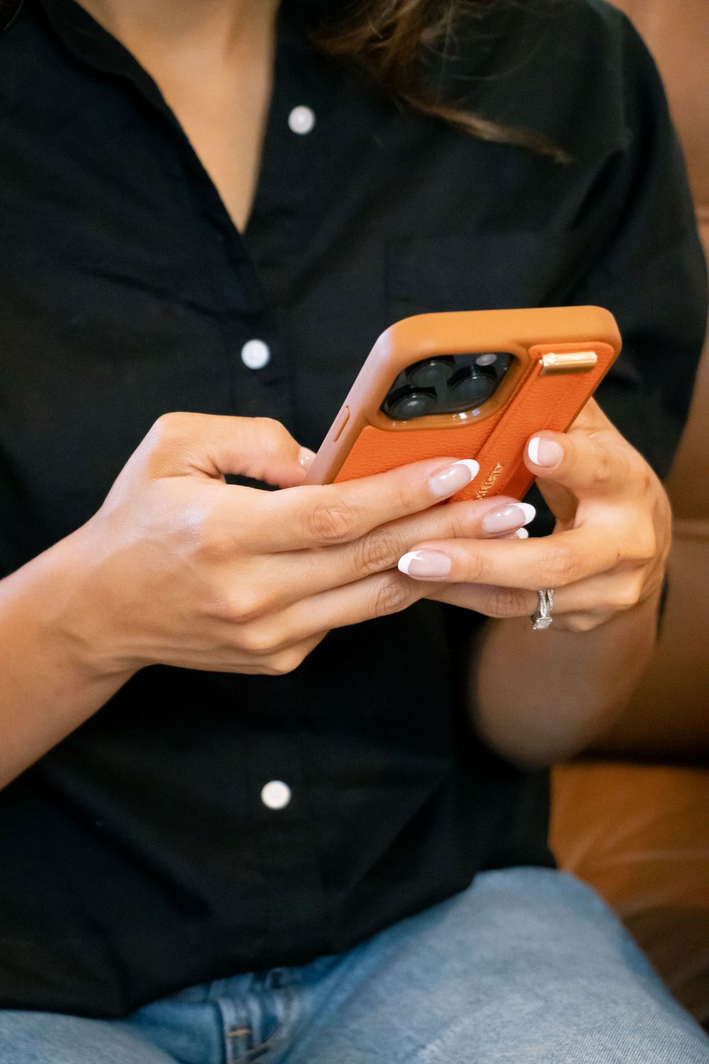 Closeup of hands holding orange phone case while texting.