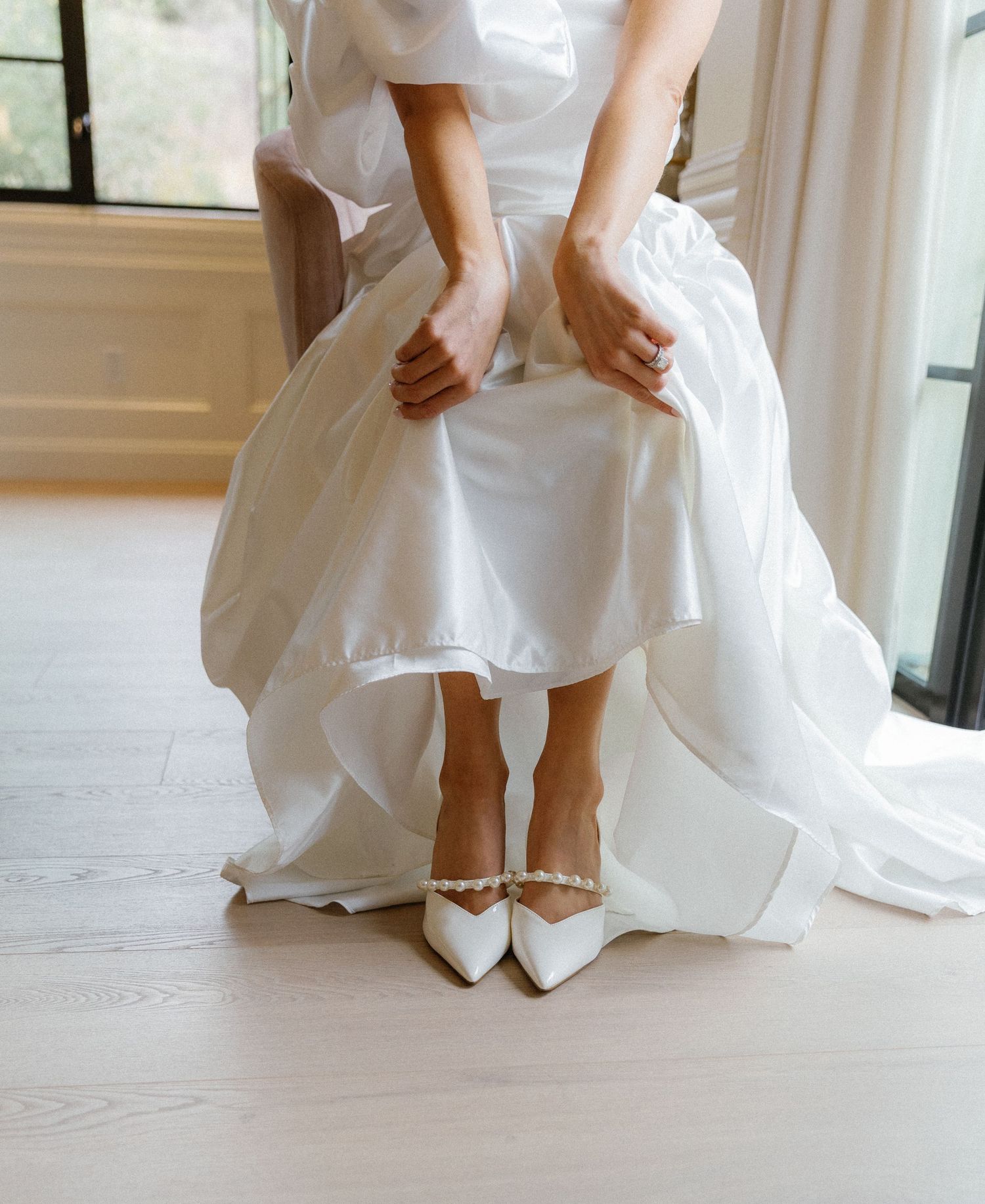 Close up view of elegant white bridal shoes beneath the flowing layers of a wedding dress.