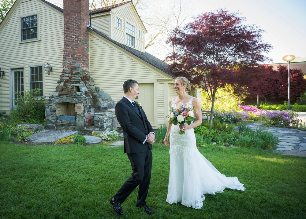 A garden wedding scene in front of a yellow house features a couple next to a beautiful Japanese maple tree.