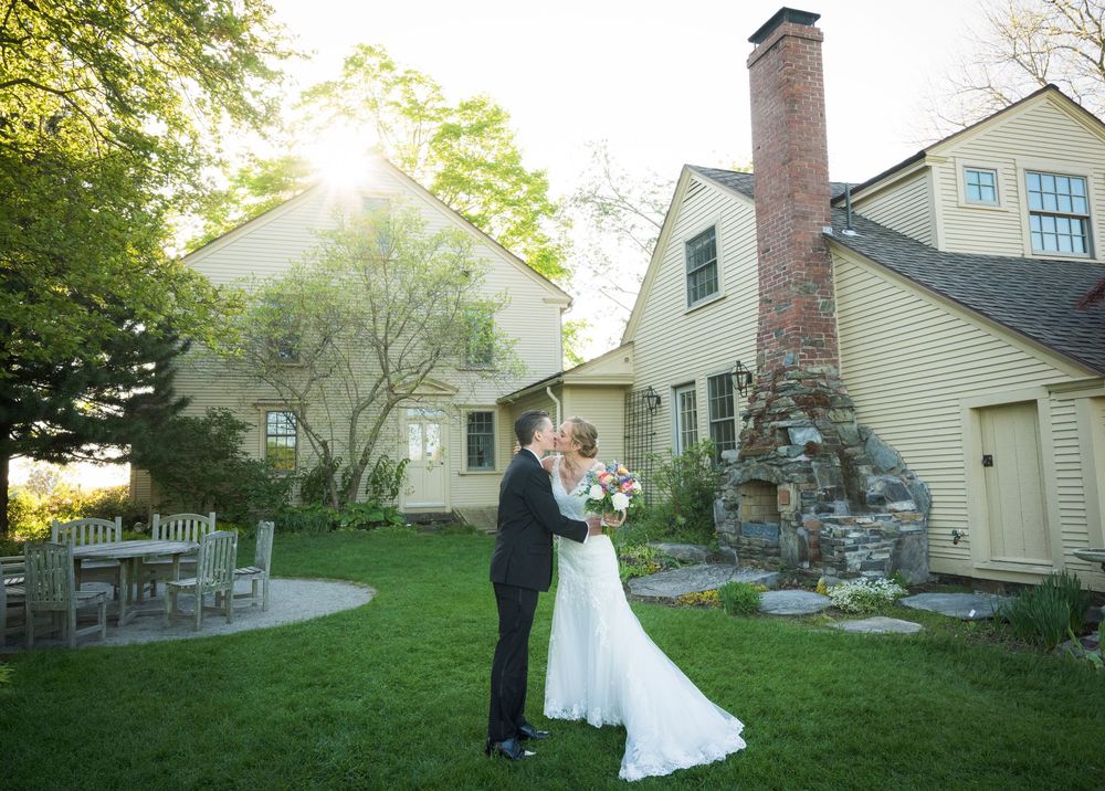 A garden wedding scene with a beautiful stone chimney and Japanese maple tree at sunset.