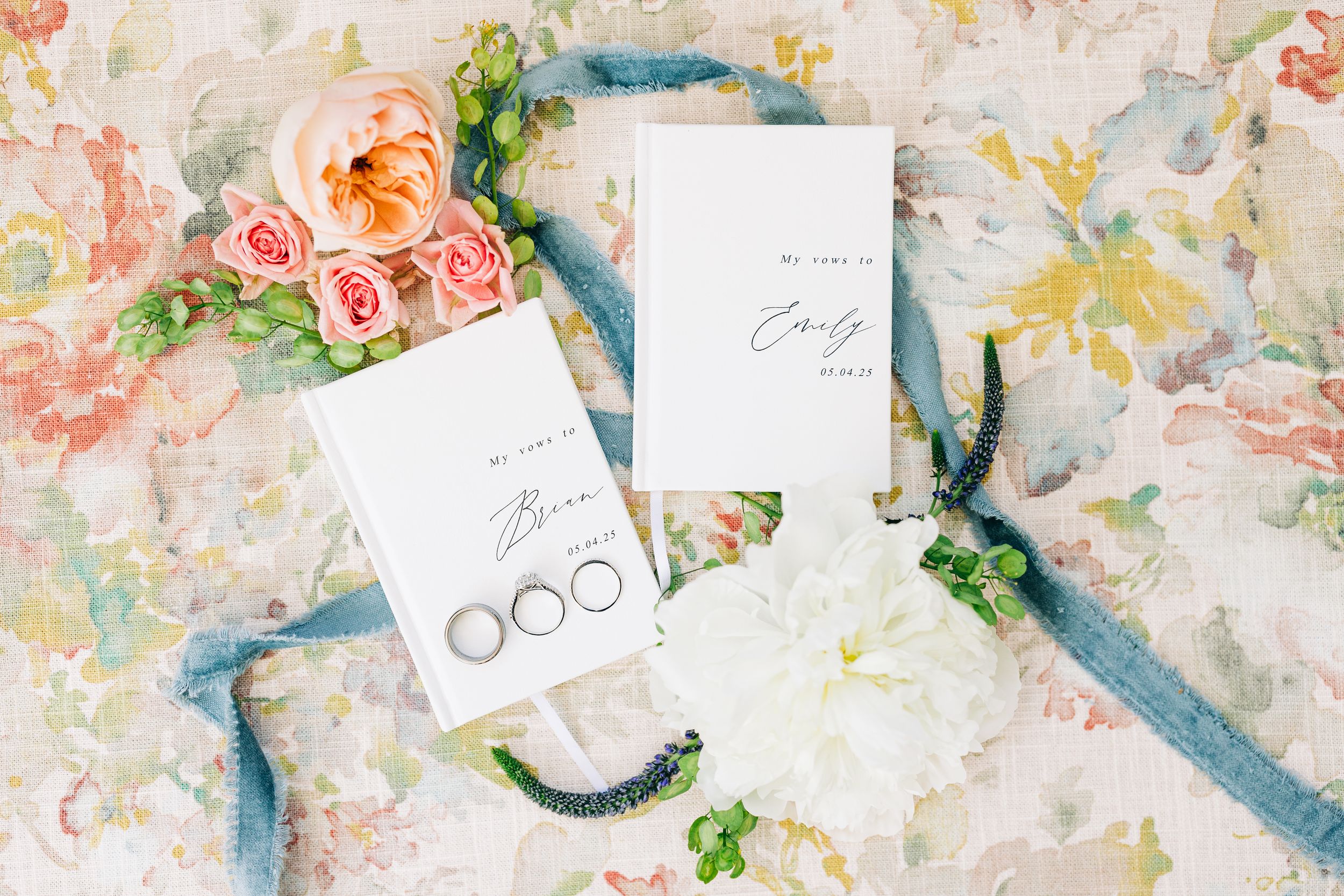 Wedding flatlay with delicate watercolor floral pattern with soft pink roses and turquoise accents on a light textured background